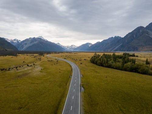 Aerial Photography of Country Road Between Green Grass Field