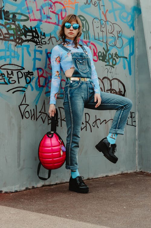 Stylish young woman standing at graffiti wall