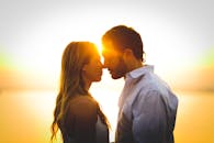 一对浪漫的情侣在水边令人惊叹的日落背景下分享了温柔的时刻