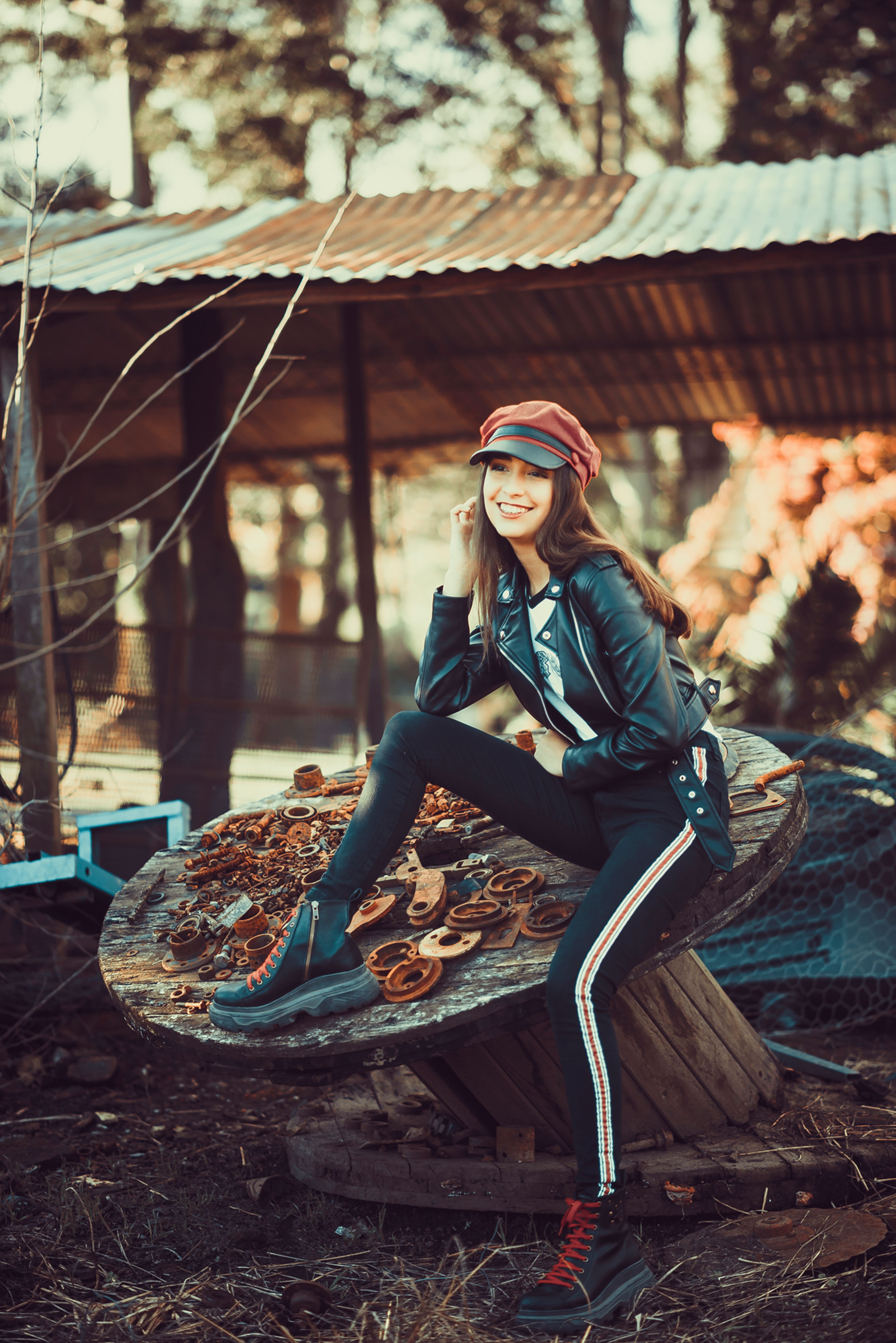 A Woman in Black Leather Jacket and Black Pants Sitting on Brown Wooden ...