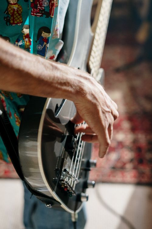 Free Detailed shot of a musician's hand strumming an electric guitar in a cozy home studio setting. Stock Photo