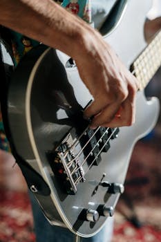 A musician's hand elegantly strumming an electric guitar during an intimate indoor performance.