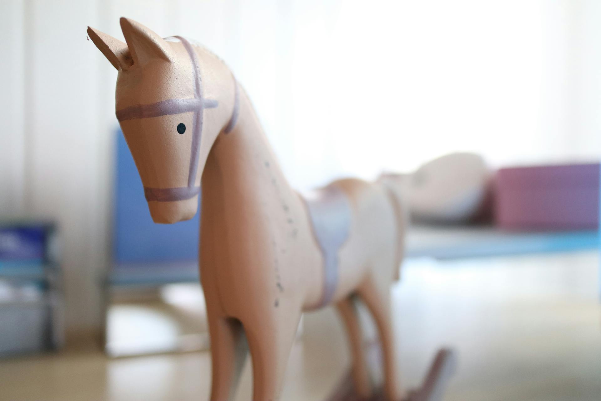 A detailed view of a miniature wooden rocking horse, indoors.