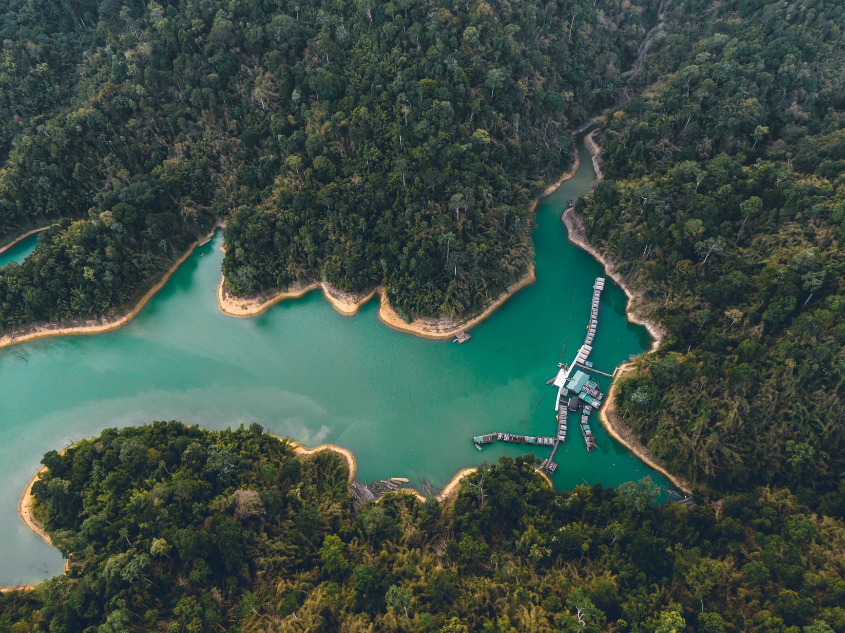 Spettacolare veduta con drone di case sull'acqua e costa sabbiosa circondata da foresta esotica e laguna