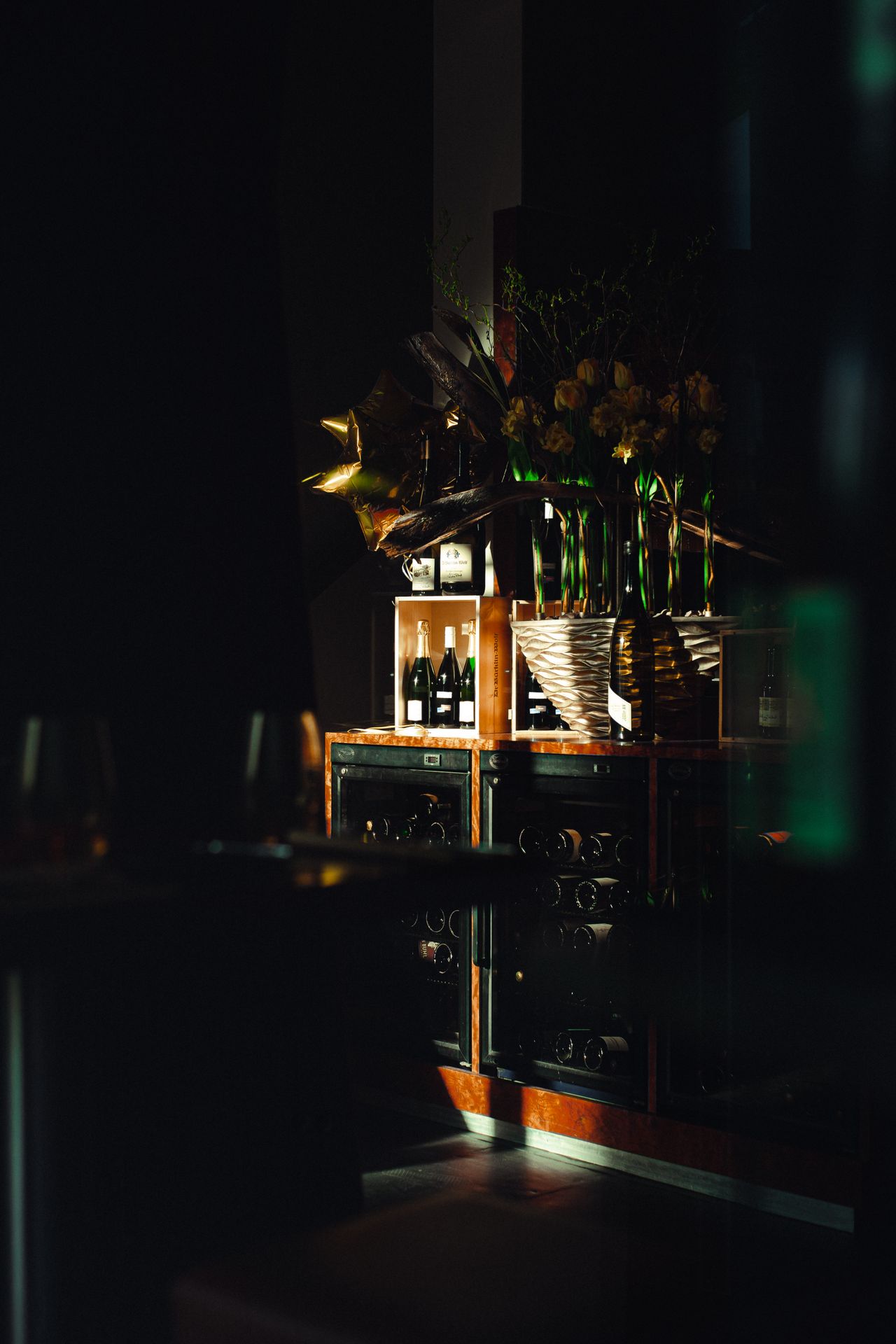 Dramatic lighting highlights a refined wine storage area with elegant decor and shadows