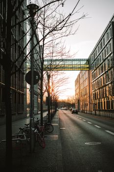 A quiet urban street with bicycles, buildings, and sunset reflections creating a serene cityscape.