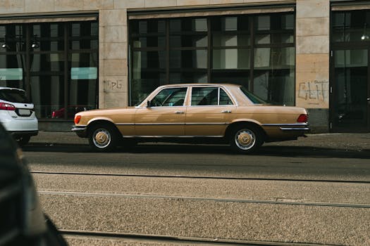 Side view of a classic gold Mercedes Benz parked on an urban street with a vintage vibe.