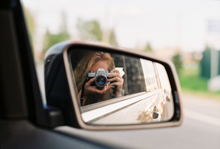 Person Taking A Self Portrait On A Rear View Mirror