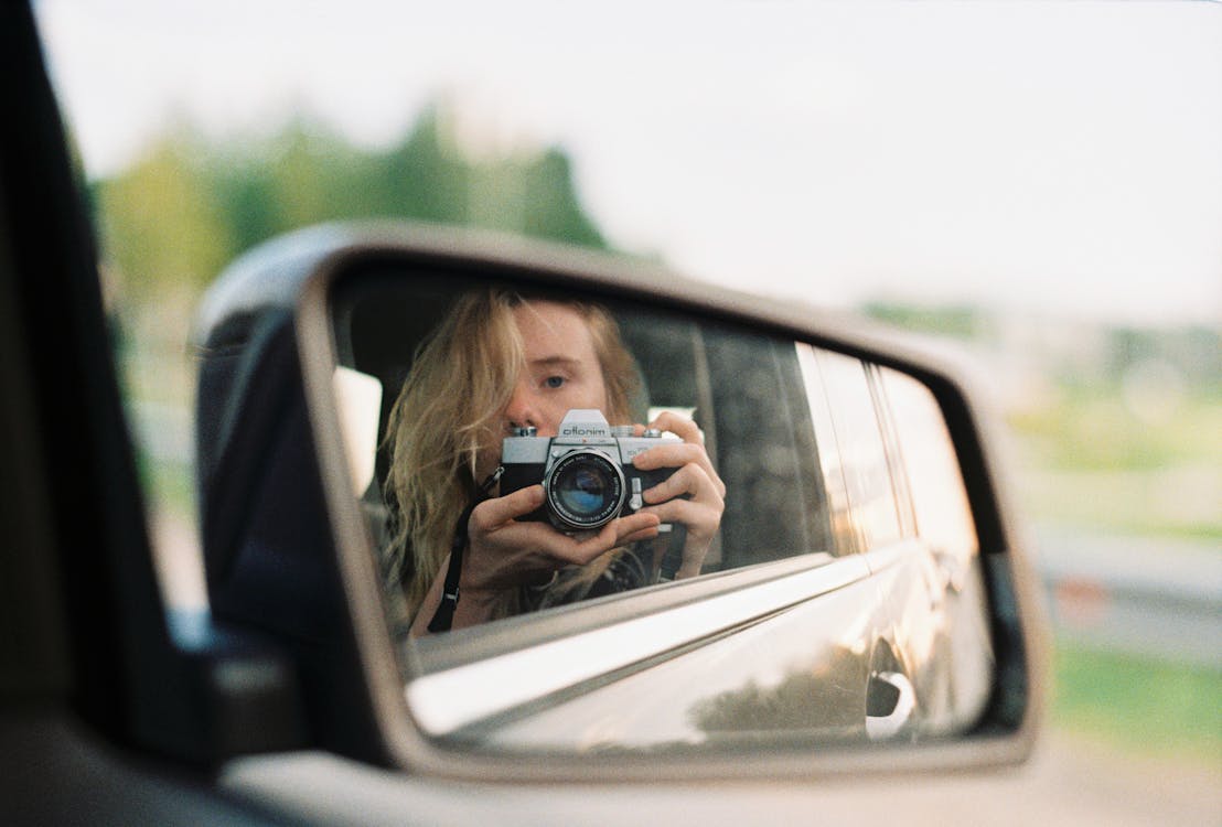 Woman Taking a Self Portrait on a Rear View Mirror