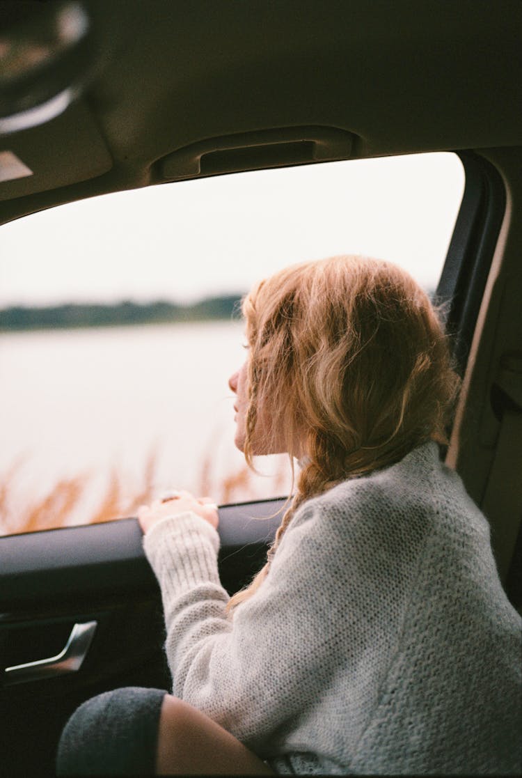 Woman In Sweater Sitting Inside Car Looking Out The Window