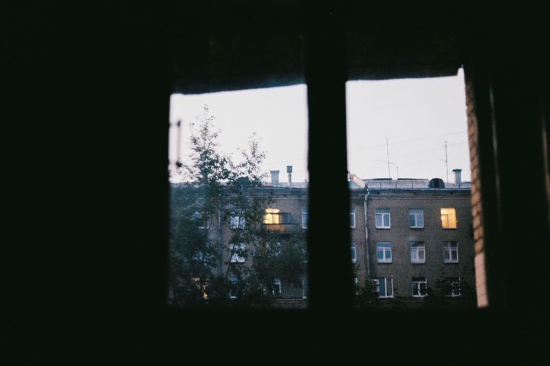 View through a window to an adjacent building during twilight, evening lighting.