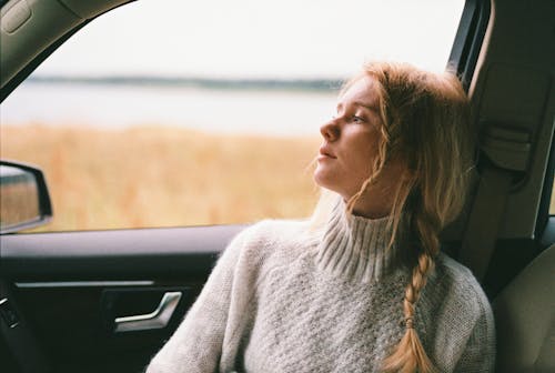 Foto de una mujer en suéter sentada dentro de un coche