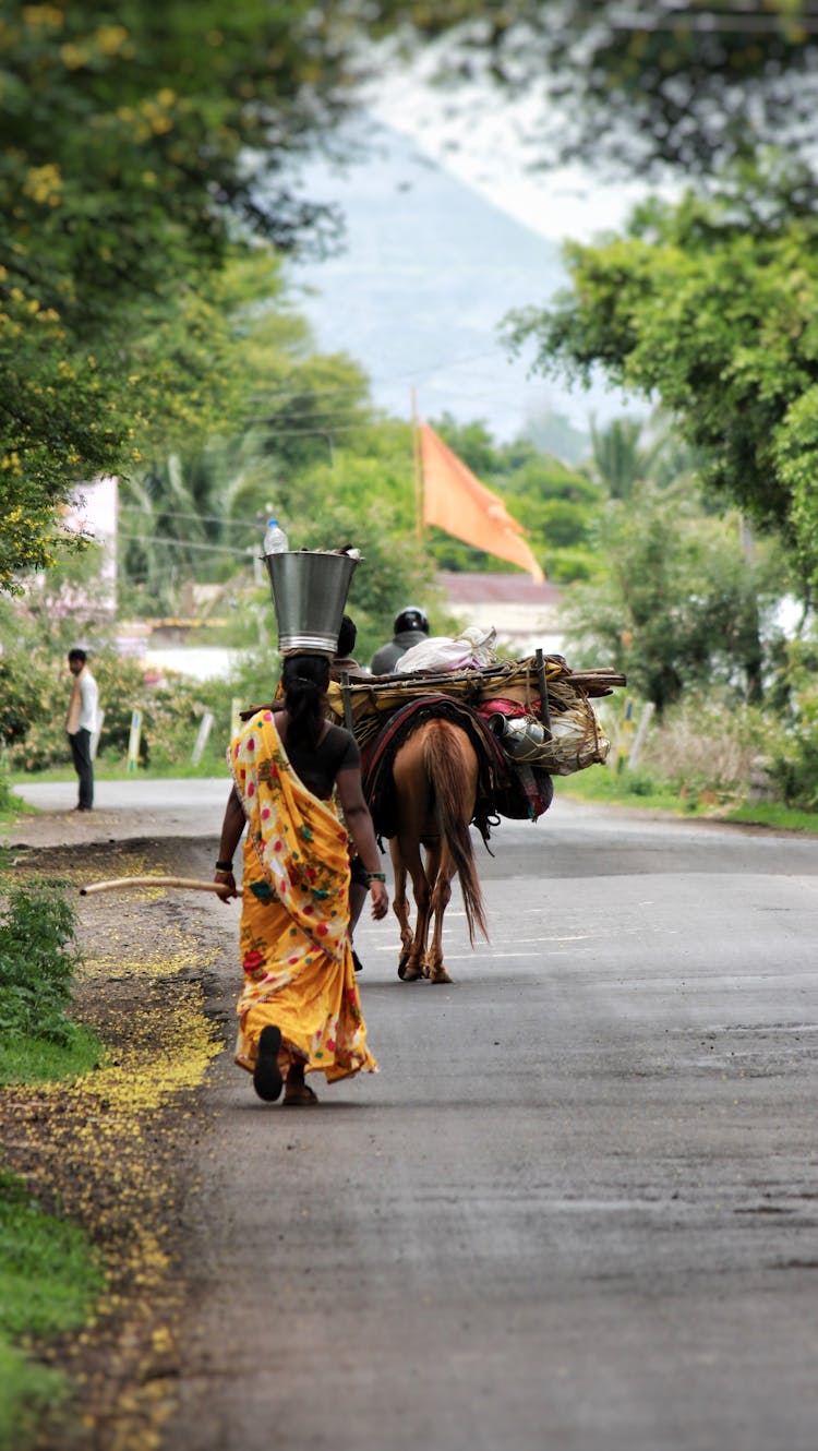 Woman In Traditional Clothes Carrying Bucket On Head