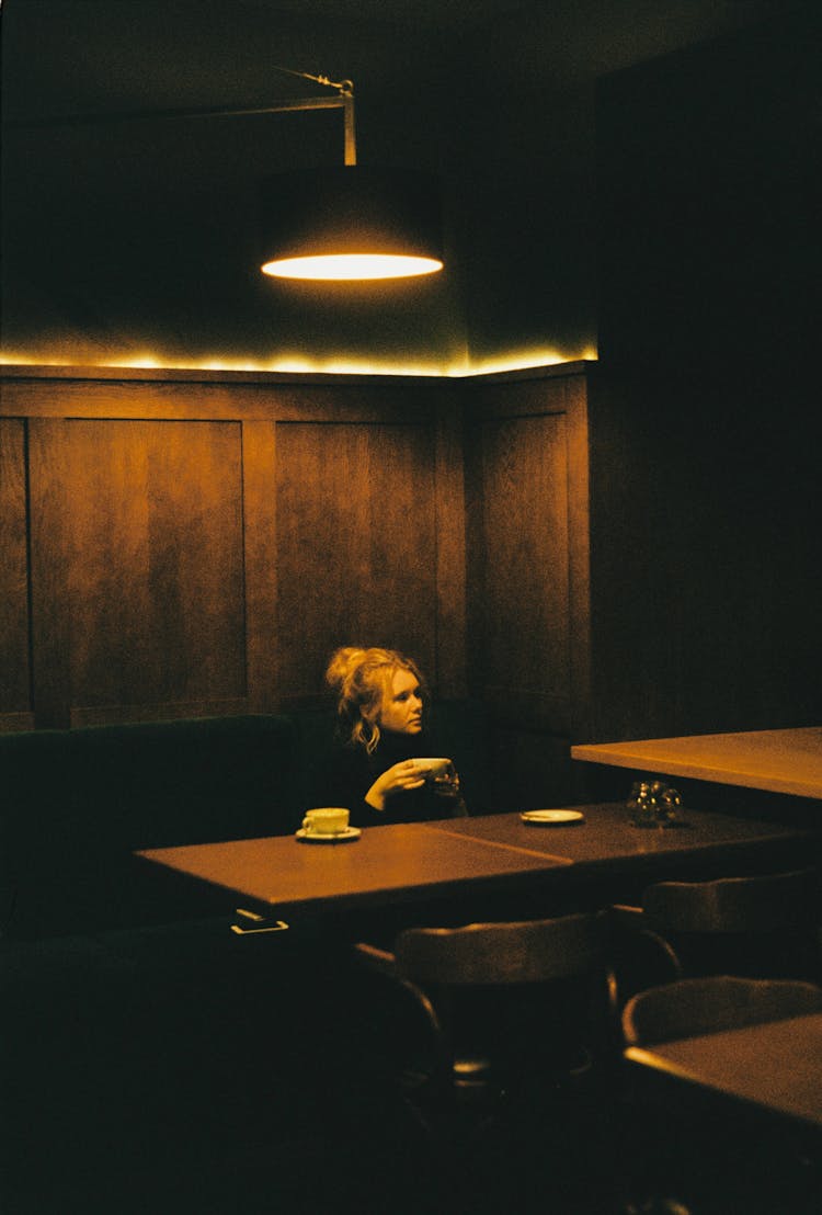 Woman Sitting At The Table In Dim Light