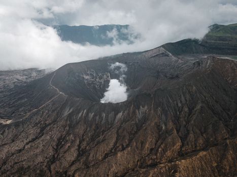 Dormant volcano near mounts on foggy day