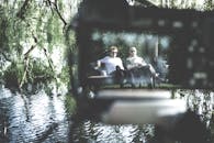 两个成年人在河畔公园的长凳上坐着，享受夏日的宁静