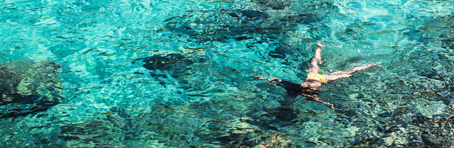 A woman snorkeling in crystal clear seawater, showcasing underwater scenery and vibrant marine life.