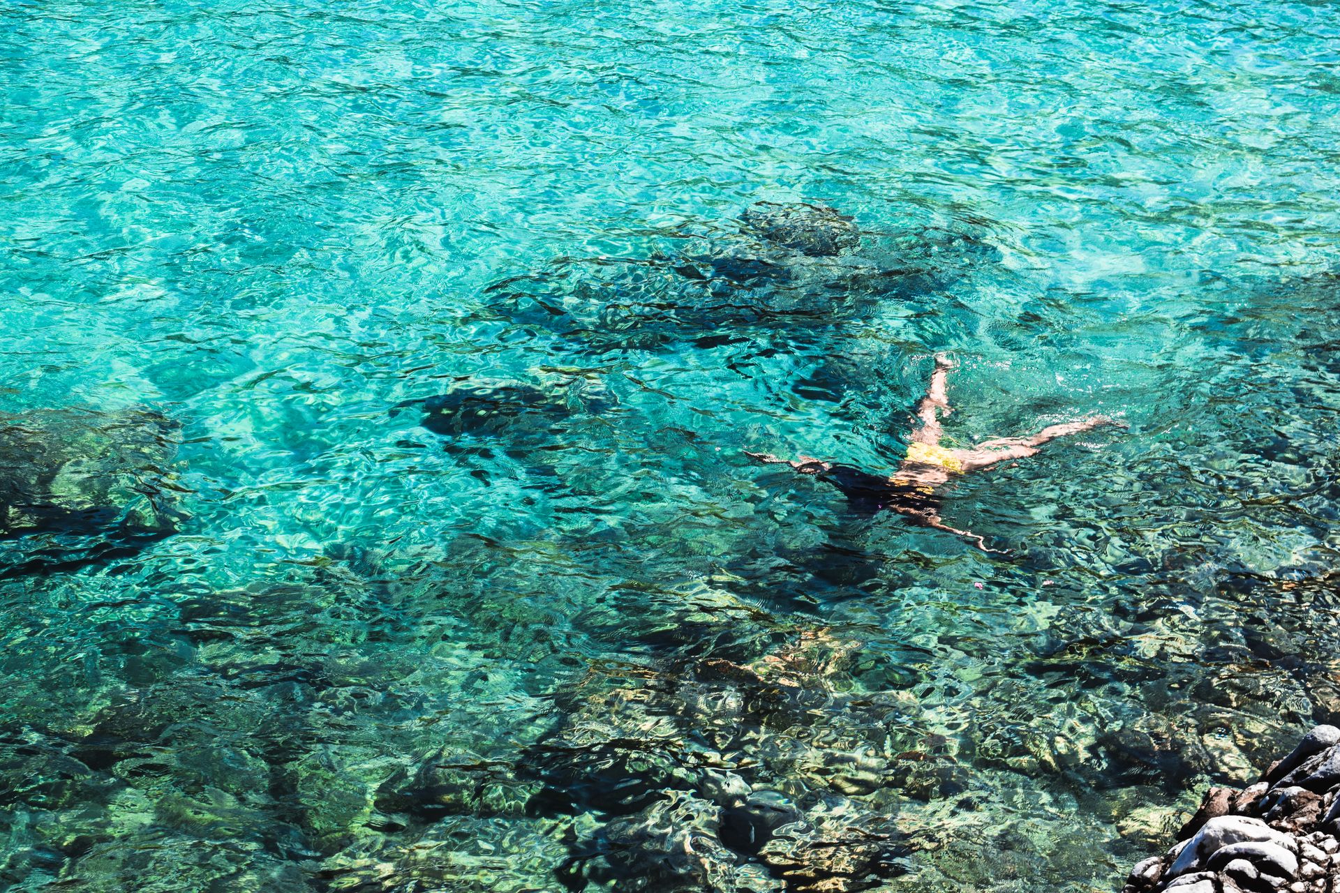 A woman snorkeling in crystal clear seawater, showcasing underwater scenery and vibrant marine life.