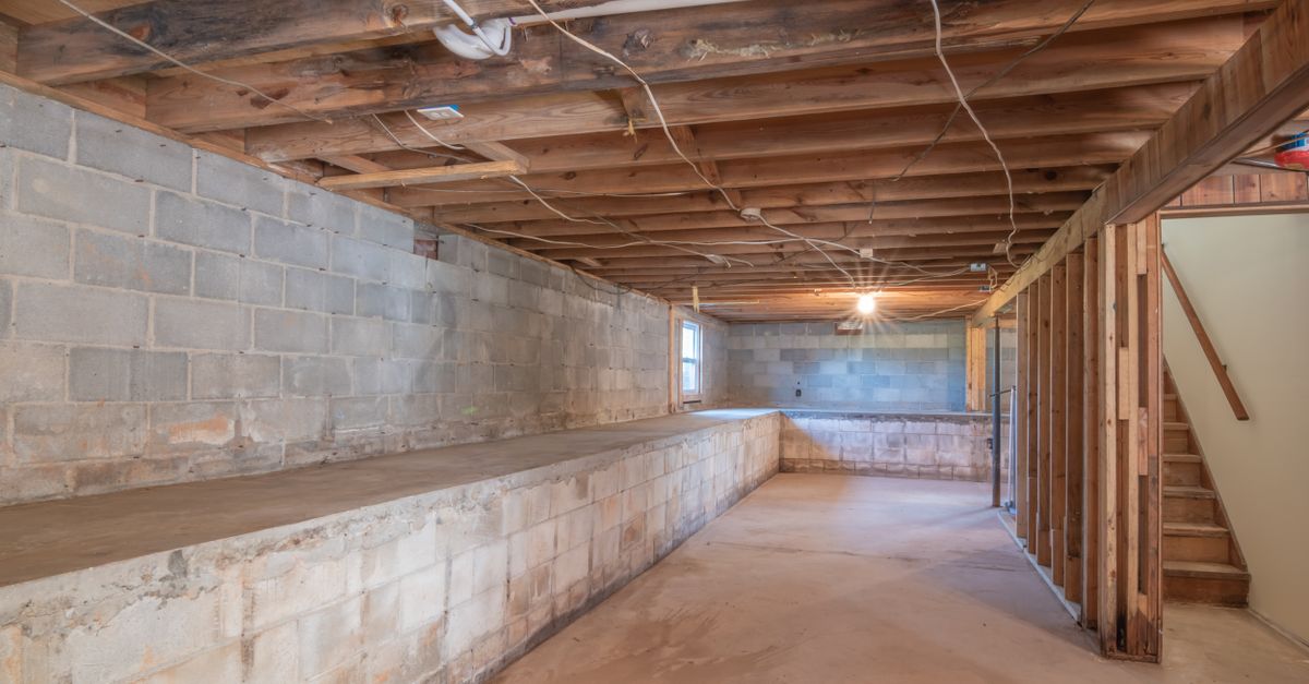 Leerer Keller mit freiliegenden Holzbalken und Betonwänden in einem Altbau