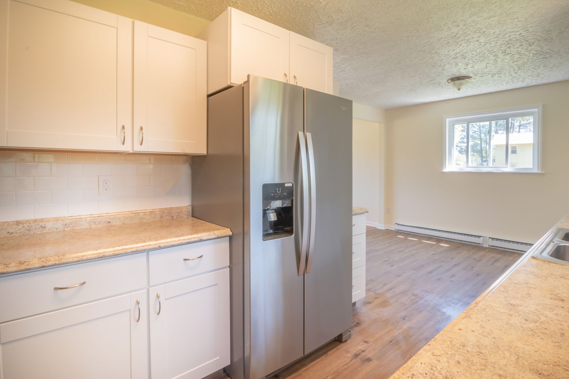 Bright modern kitchen featuring stainless steel appliances and wooden flooring.