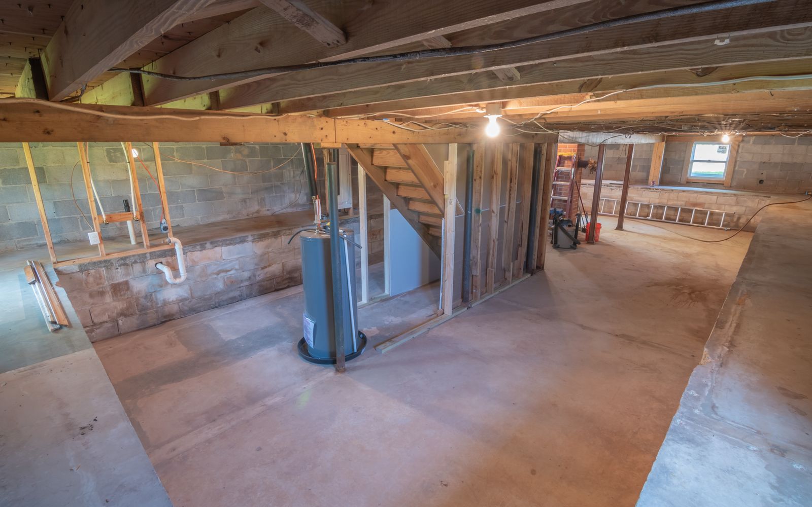 Empty basement interior with exposed beams and pipes