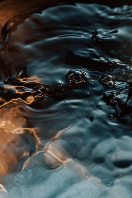 From above textured background of translucent rippled water flow with small drops and shiny surface
