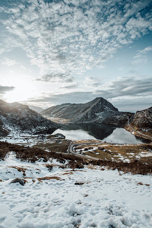 Picturesque mountains reflecting in pond under cloudy sky in wintertime