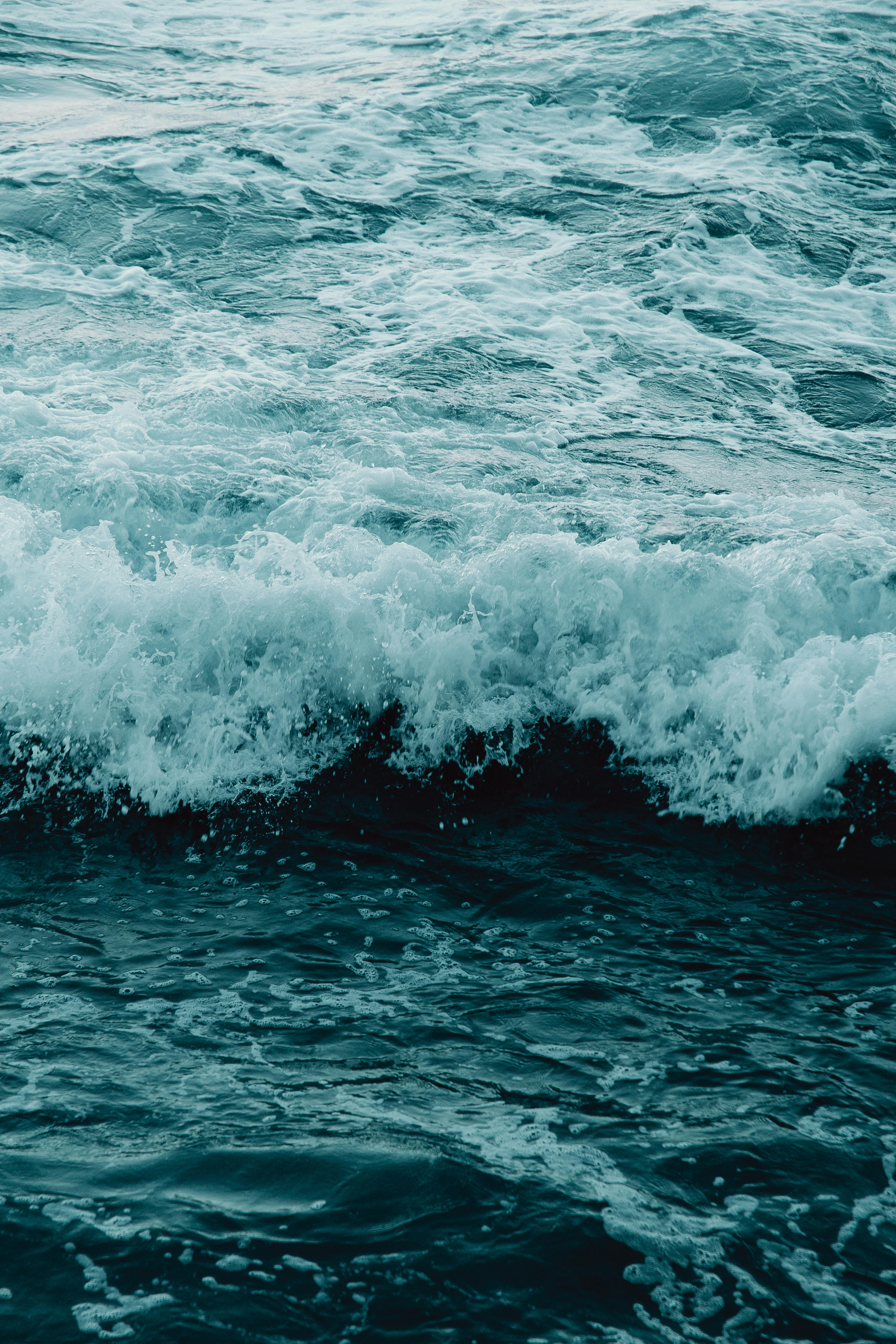 From above breathtaking view of tempestuous splashing ocean waves with rippled water and foam on surface in daylight