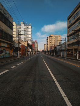 Straight asphalt road with marking lines between contemporary style multistage house exteriors under blue cloudy sky in city in daylight