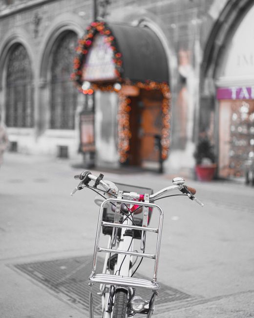 A bicycle parked on a charming street in Munich, adorned with festive lights.