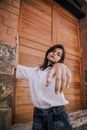 Trendy ethnic woman standing with reached arm near brick wall