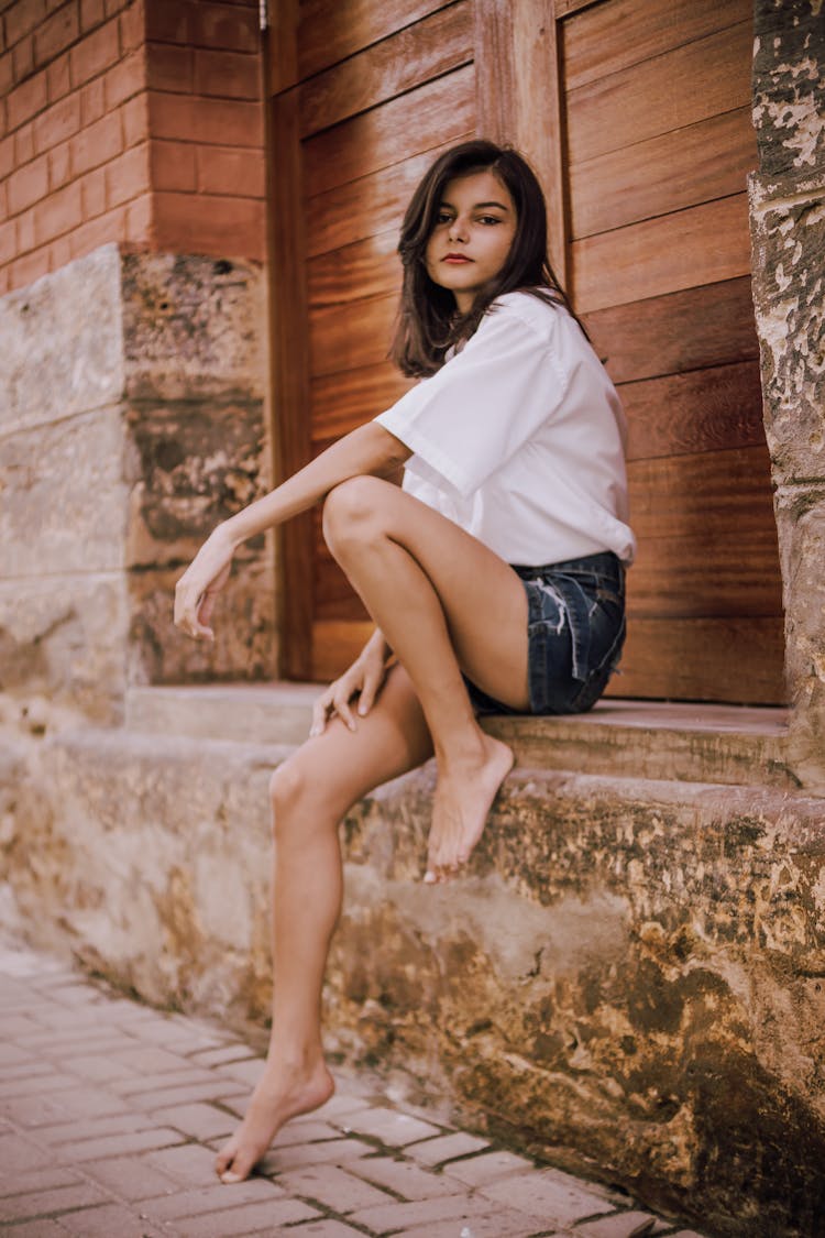 Trendy Ethnic Woman Sitting On Old Stone Building Surface