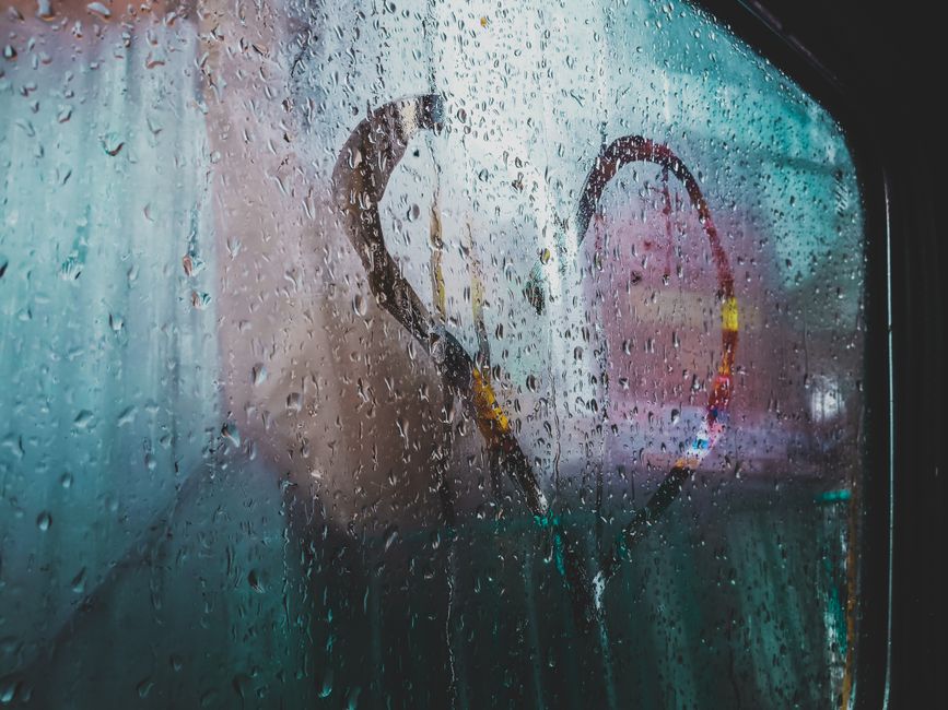 Heart on misted glass as symbol of love with water flow and drips on surface in public transport in evening in rainy weather