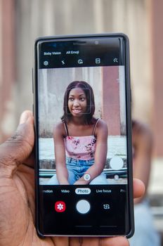 Close-up of a smartphone displaying a young woman's portrait in Lagos.