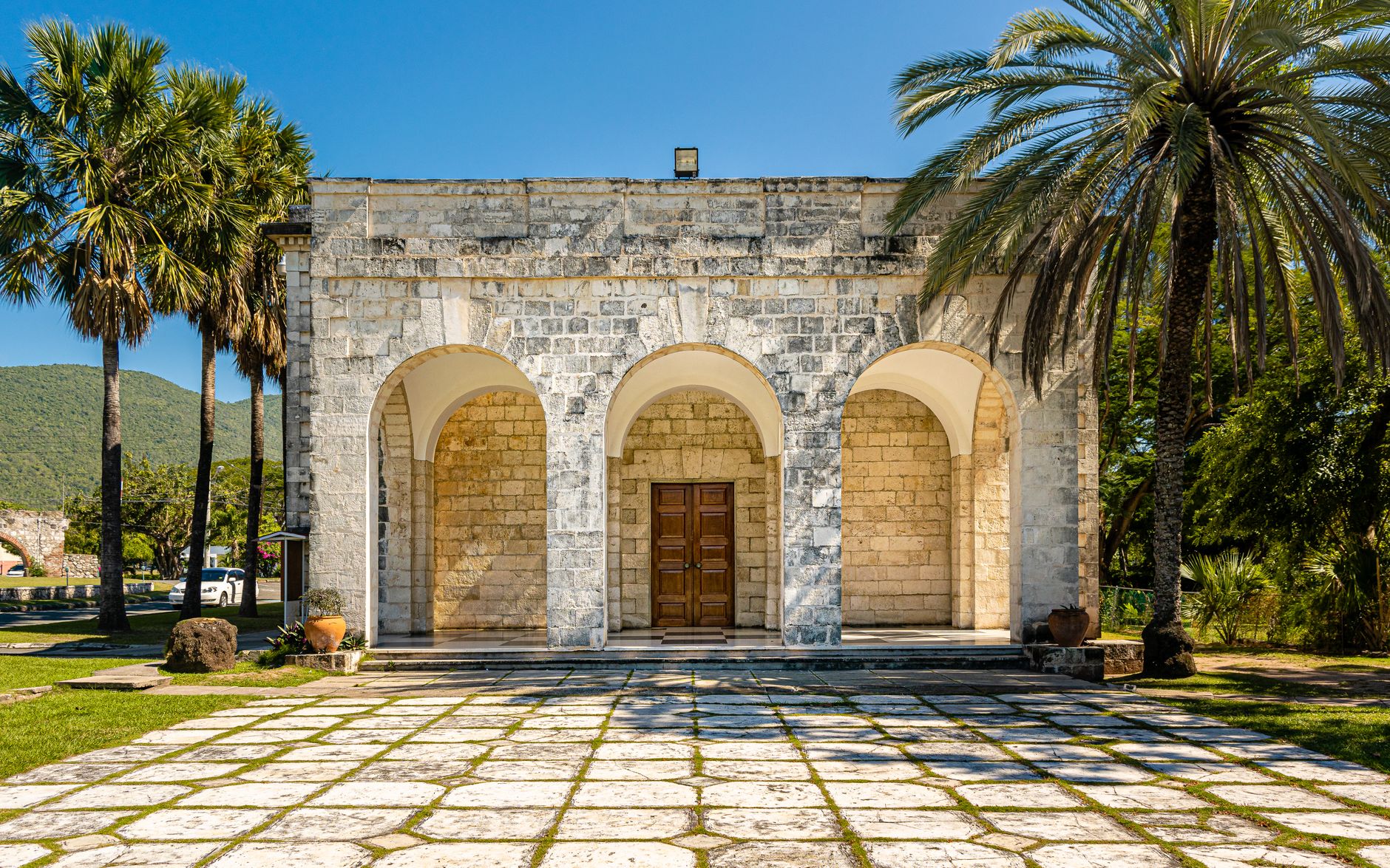 Old stone structure with arched entrance surrounded by palm trees in Kingston, Jamaica.. Photo by Kenrick Baksh on Pexels