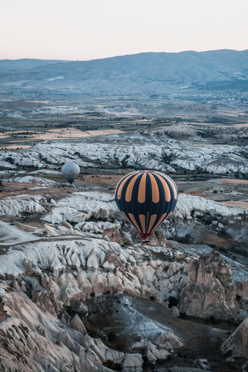 Free Scenic aerial view of hot air balloons floating over Cappadocia's unique rock formations. Stock Photo