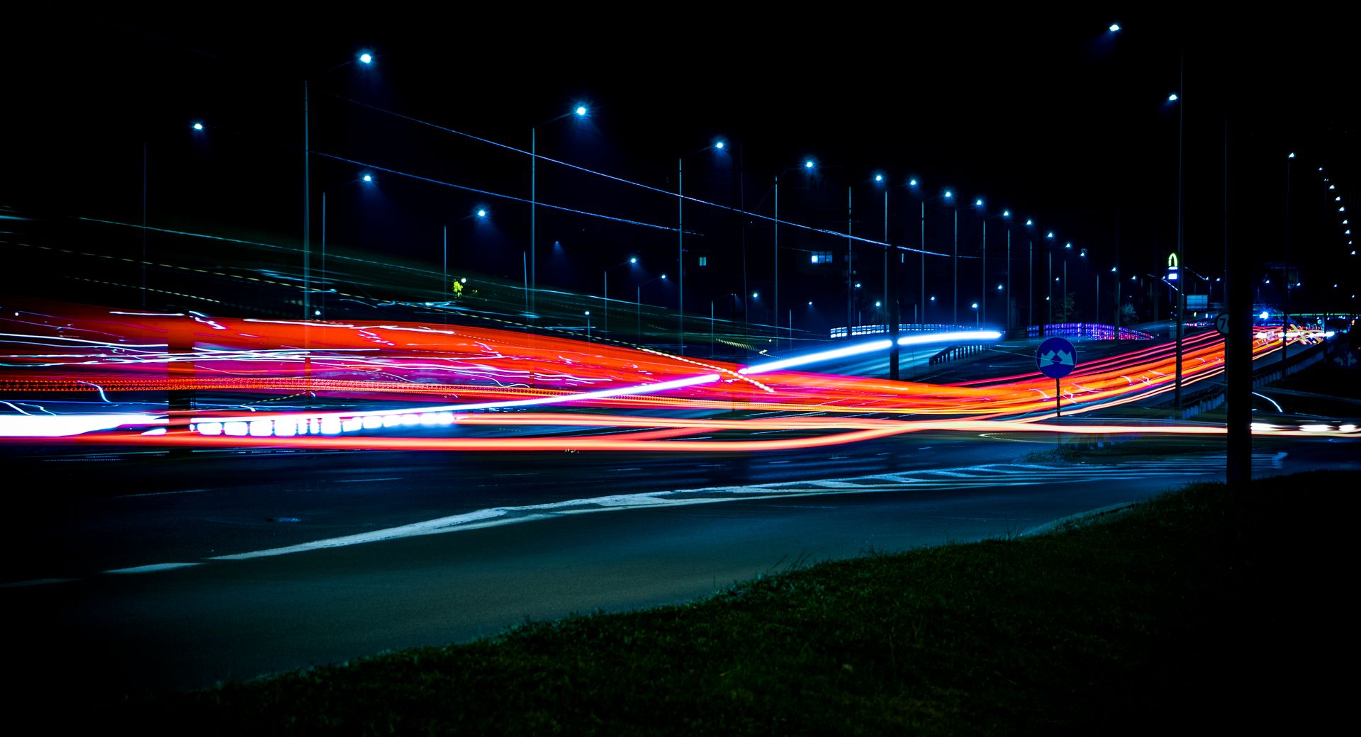 Long exposure photo of a highway at night with vibrant light trails and streetlights.