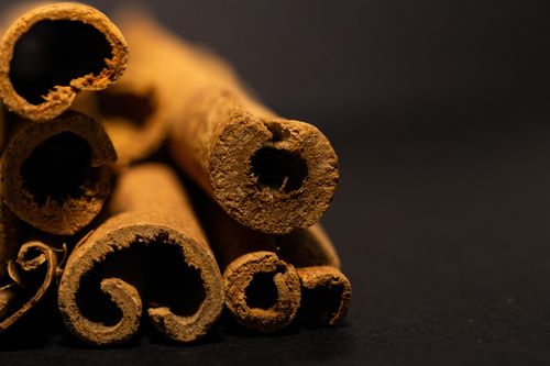 Free Detailed close-up of aromatic cinnamon sticks on black background, showcasing texture and depth. Stock Photo