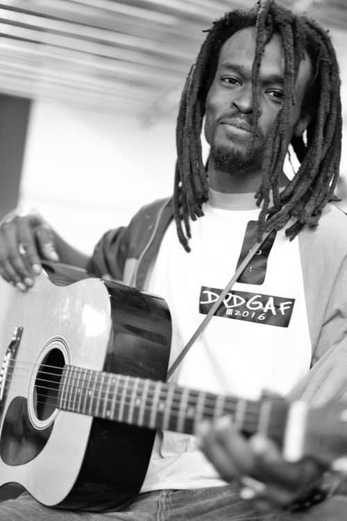 Free Black and white of African American man with dreadlocks smiling at camera while playing acoustic guitar Stock Photo