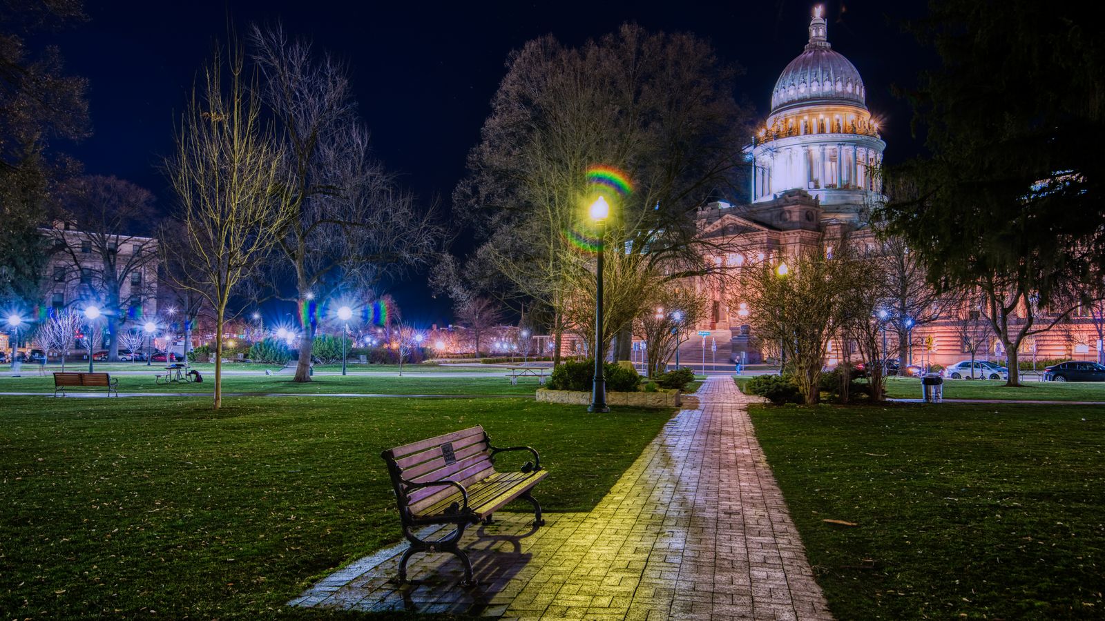 Empty pathway with bench and lantern among leafless trees on background of glowing Saint Isaac Cathedral at night time