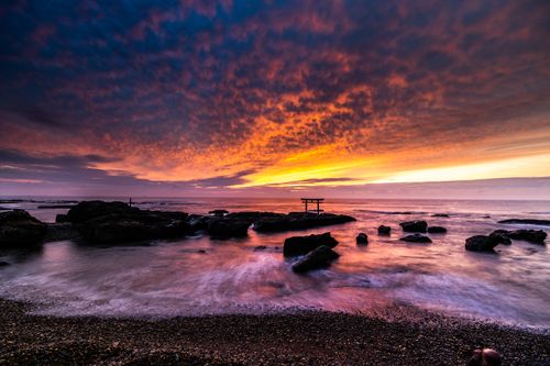 Free Long exposure of waves washing pebble beach with cliffs and rocks in sea against glowing sundown Stock Photo