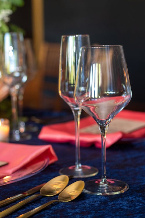 Table setting with shiny crystal wineglasses and golden cutlery on blue tablecloth for banquet