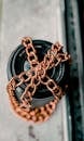 Top view of modern black lens of camera with golden chain accessory on white surface