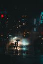 这是一个戏剧性的、喜怒无常的场景，夜晚的雨中，人们撑着伞穿过街道