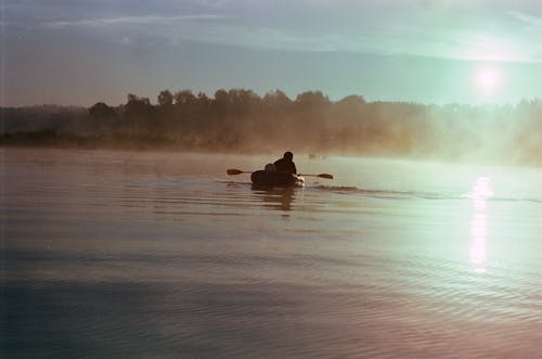 Anonymous man in boat on misty lake