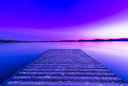 Wooden pier above glowing purple lake