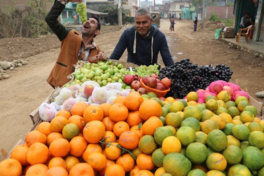 Vibrant street fruit market with vendor in Hetauda, featuring fresh oranges, grapes, and more.