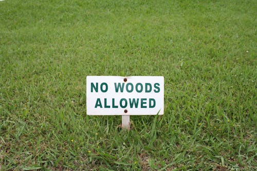 White No Woods Allowed Sign on Green Grass Field