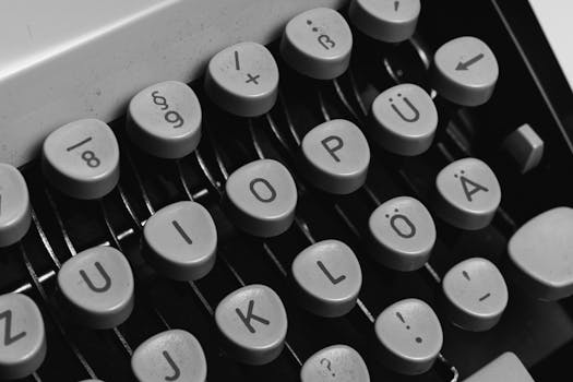 Close-up of vintage typewriter keys, showcasing classic design in black and white.