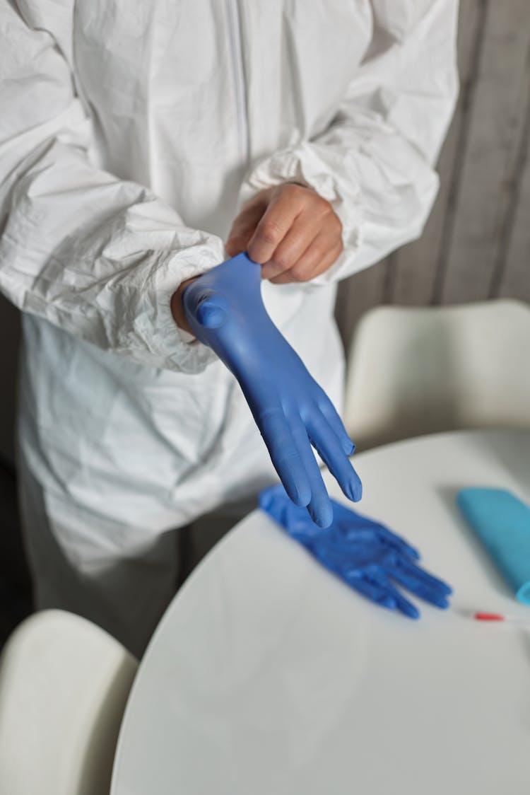 A Person In PPE Wearing A Latex Glove